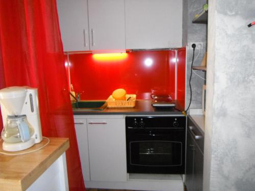 - une cuisine rouge avec cuisinière et four micro-ondes dans l'établissement T2 Cabine MARSEILLAN PLAGE, à Marseillan