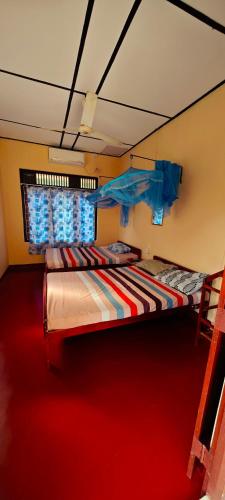 a bedroom with two beds and a red carpet at Tony's Garden House Back Packers inn in Jaffna