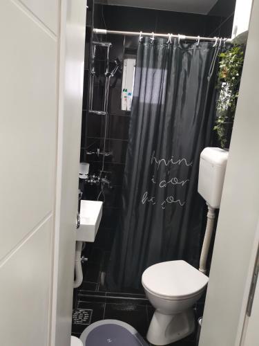a bathroom with a toilet and a black shower curtain at Stan na dan Pozarevac Apartman Olja in Požarevac
