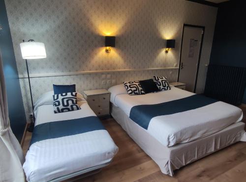 two beds in a small room with two lamps at Le Pavillon Saint-Martin in Souillac