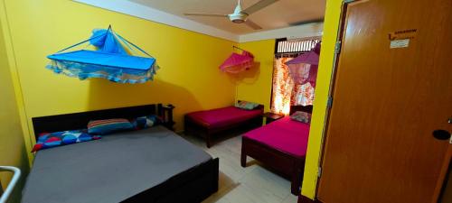 a room with two beds and a yellow wall at Tony's Garden House Back Packers inn in Jaffna