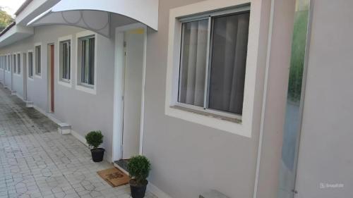 a white building with windows and potted plants on a sidewalk at Casa1sn - Casa completa com jardim privativo e chuveirão refrescante! in Serra Negra