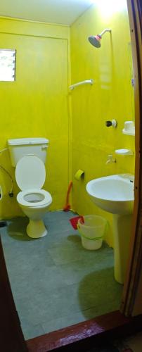 a yellow bathroom with a toilet and a sink at Tony's Garden House Back Packers inn in Jaffna