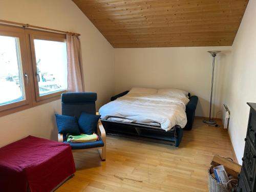 ein Schlafzimmer mit einem Bett und einem Stuhl und einem Fenster in der Unterkunft Ferienwohnung Edelweiss, in Splügen