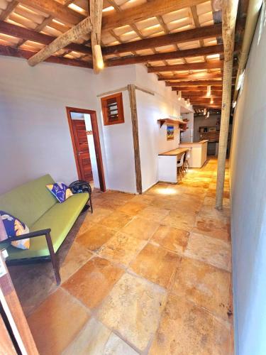 a living room with a green couch and a kitchen at Chalés Mahalo J - Pontal de Maceió - Fortim in Fortim