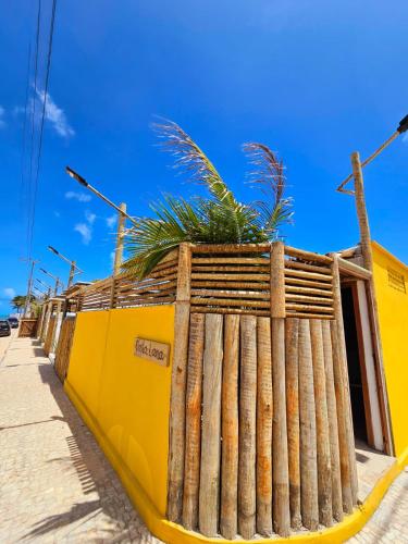 a fence with plants on top of a yellow building at Chalés Mahalo J - Pontal de Maceió - Fortim in Fortim
