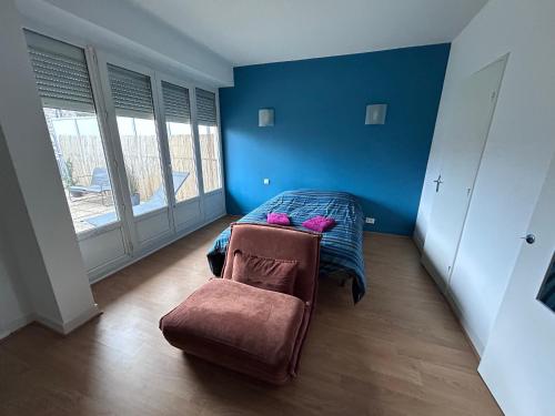 a blue bedroom with a bed and a chair at Appartement centre ville et terrasse in Brive-la-Gaillarde