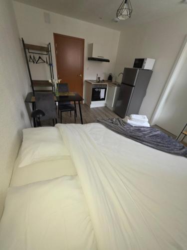 Cet appartement comprend une chambre avec un lit blanc et une cuisine. dans l'établissement studio cactus, à Mulhouse