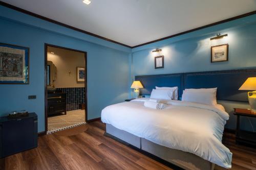 a blue bedroom with a large bed with white sheets at Akara House Sukhothai - Luxury Riverside Residence in Sukhothai