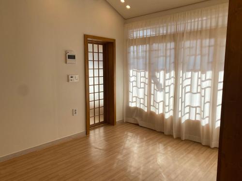 an empty room with a large window and a door at Bonjour Hanok in Gyeongju