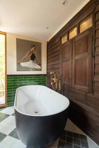 a large bath tub in a bathroom with green tiles at Akara House Sukhothai - Luxury Riverside Residence in Sukhothai