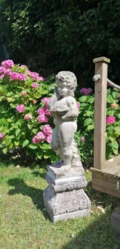 a stone statue in a garden with flowers at Le Derrien in La Roche-Derrien