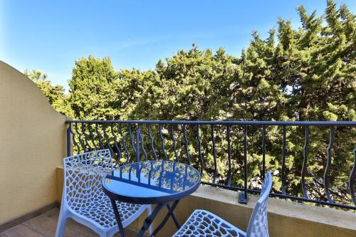 a blue table and chairs on a balcony with trees at Le Petit Prince in Sainte-Maxime