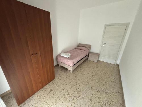 a small bedroom with a bed and a wooden closet at Il Vespro Apartment in Montegiorgio