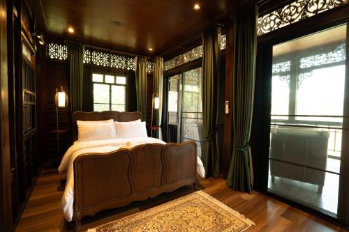 a bedroom with a bed and some windows at Akara House Sukhothai - Luxury Riverside Residence in Sukhothai