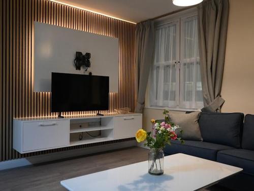 a living room with a couch and a flat screen tv at Central located apartment with parking in Cheltenham