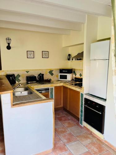 a kitchen with brown cabinets and a white refrigerator at Le Petit Usar in Loubens