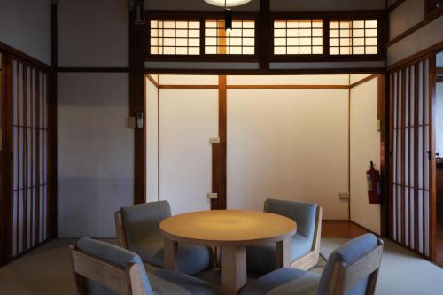 einen Tisch und Stühle in einem Zimmer mit Fenstern in der Unterkunft Machiya Posong in Taitung