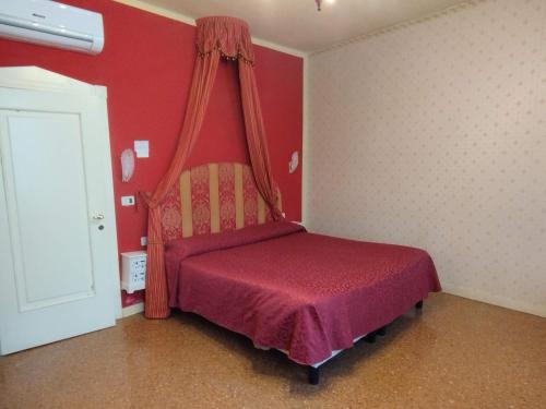 a bedroom with a bed with a red wall at Alloggi Acquavita - checkin at "Alloggi SS Giovanni e Paolo" in Venice