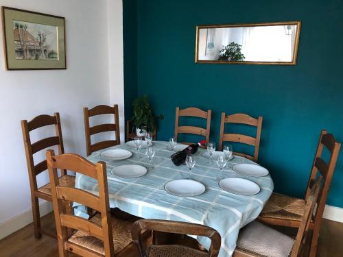 une table à manger avec des chaises et un mur bleu dans l'établissement Chambre Océan, parking gratuit et jardin, à Besançon
