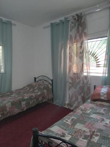 a hotel room with two beds and a window at Leith Holiday Home in ‘Ayn Jannā