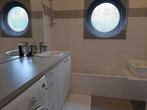 La salle de bains est pourvue de 2 lavabos, d'une baignoire et de 2 fenêtres. dans l'établissement Le jardin de la Baie-face plage du Trez & thalasso, à Bénodet