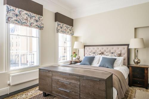 a bedroom with a large bed and two windows at Bespoke Central Town House in Bath
