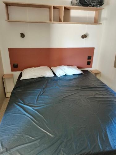 un lit avec deux oreillers dessus dans une chambre dans l'établissement Mobil-home Comfort XL 3 chambres 6 pers, au Grau-du-Roi