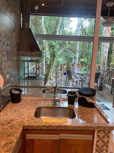 a kitchen with a sink and a large window at Casa em Juquehy com muita natureza in São Sebastião