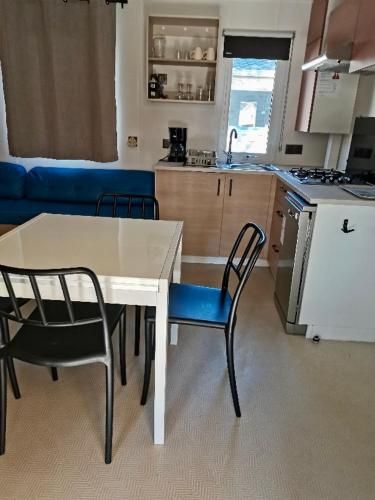 Il comprend une cuisine avec une table, deux chaises et une table. dans l'établissement Mobil-home Comfort XL 3 chambres 6 pers, au Grau-du-Roi
