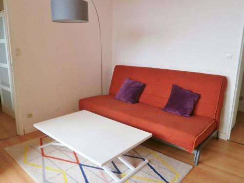 un canapé rouge avec deux coussins violets et une table dans l'établissement Appartement 6 personnes Gruissan, à Gruissan