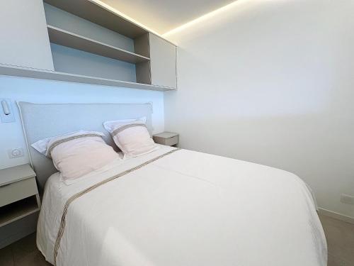 une chambre avec un lit blanc avec deux oreillers dans l'établissement 39m2 Croisette, terrasse, vue mer, garage, à Cannes