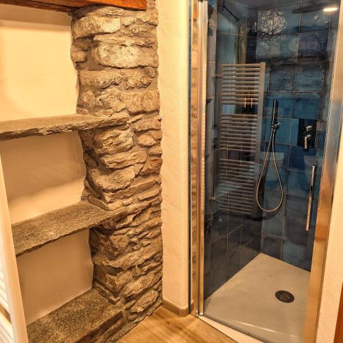 a shower in a bathroom with a stone wall at Le Foyer de Grand-mère in Fenis