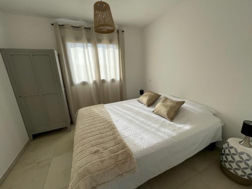 une chambre avec un lit blanc avec deux oreillers dessus dans l'établissement Magnifique appartement T2, à Cuttoli-Corticchiato