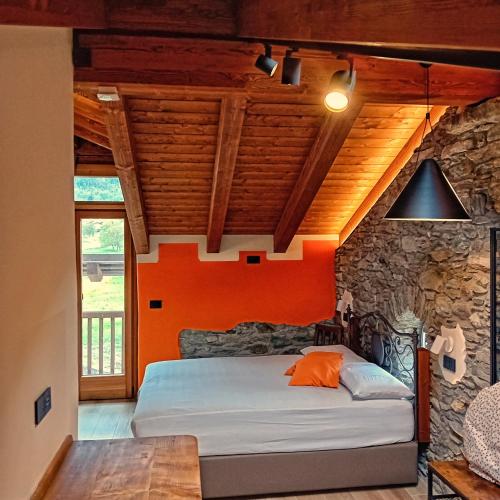 a bedroom with an orange wall and a bed at Le Foyer de Grand-mère in Fenis