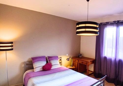 a bedroom with a bed with purple sheets and two lamps at La petite maison de Valérie proche château de la Rode, du Domaine de Flore et du Lac Saint Ferréol in Lempaut