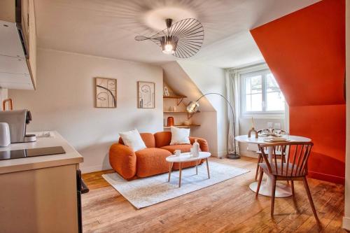 un salon avec un canapé orange et une table dans l'établissement Logement Cozy décoré avec gout, à Caen