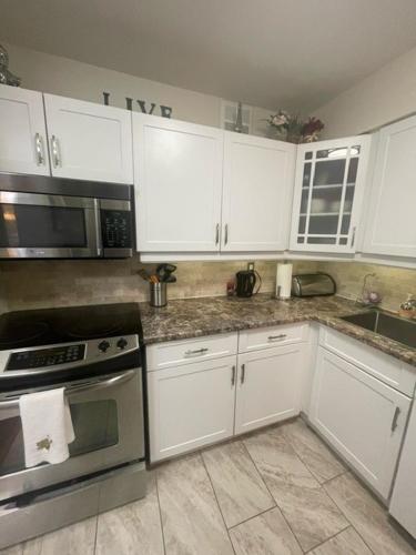 a kitchen with white cabinets and stainless steel appliances at Welcoming homestay with relaxing private room in Oakville