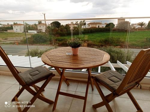 a wooden table and two chairs in front of a window at Blue Seaview Appartments in Paphos City
