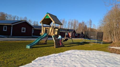 un niño jugando en un parque infantil con un tobogán en Stor älg, en Dalskog