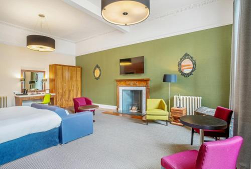 a hotel room with a bed and chairs and a fireplace at The Place Hotel in Edinburgh