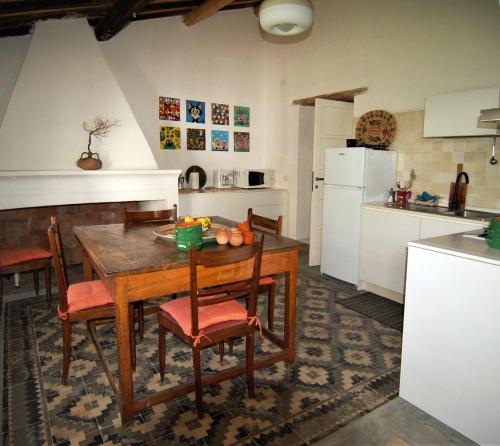 a kitchen with a wooden table and chairs and a kitchen with white appliances at Casa Manamunda in San Vero Milis