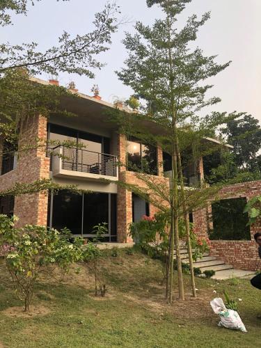 a brick house with a balcony and trees at Farm House in Muksūdpur