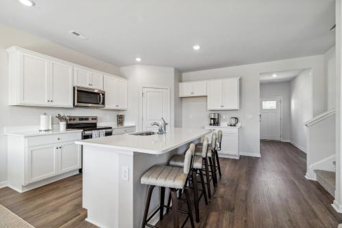a kitchen with white cabinets and a large island with bar stools at Luxury 5BR Home Minutes from Wilmington Beaches in Scotts Hill
