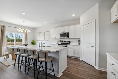 a kitchen with white cabinets and a large island with bar stools at Luxury 5BR Home Minutes from Wilmington Beaches in Scotts Hill