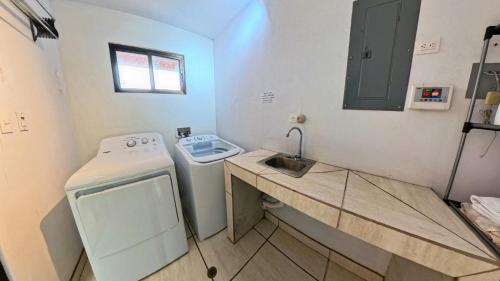 a small bathroom with a sink and a washing machine at Vista Mundo Centrar in San Ramón