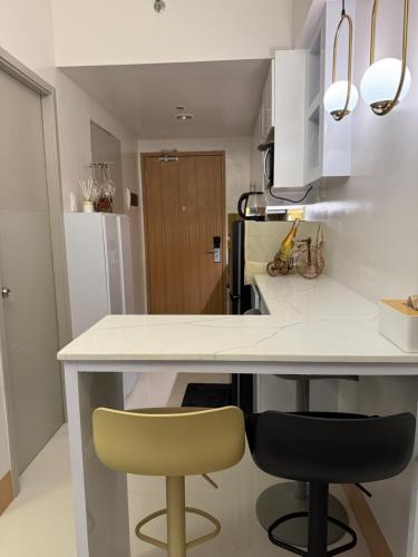 a kitchen with a white counter and two chairs at Glamorous SMDC Shore 3, 5 Star Rate BnB-Wifi-Netflix in Manila