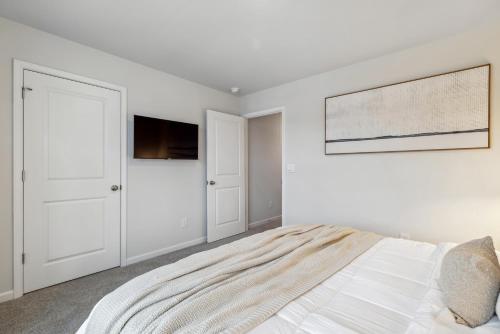a white bedroom with a bed and a flat screen tv at Luxury 5BR Home Minutes from Wilmington Beaches in Scotts Hill