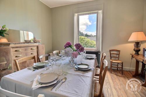 une table à manger avec un chiffon de table blanc et une fenêtre dans l'établissement Roz vallee 1, à Perros-Guirec
