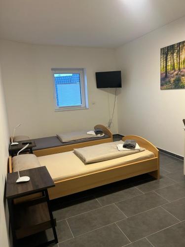 a bedroom with two beds and a tv on the wall at Pension Imhof in Oyten